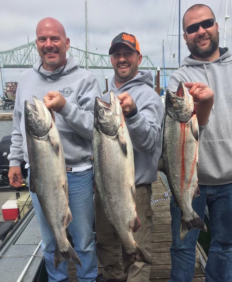 fishermen holding up silver chinook salmon caught with fishing charter in Oregon
