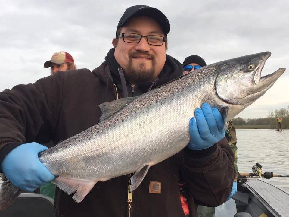 fisherman holding up silver chinook salmon caught with fishing charter in Oregon