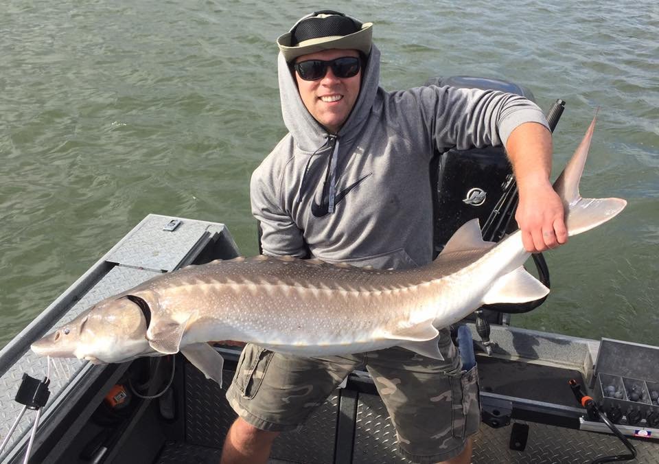 fisherman holding up sturgeon caught with fishing charter in Oregon