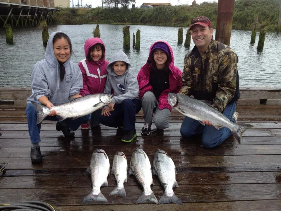 family holding up silver chinook salmon caught with fishing charter in Oregon