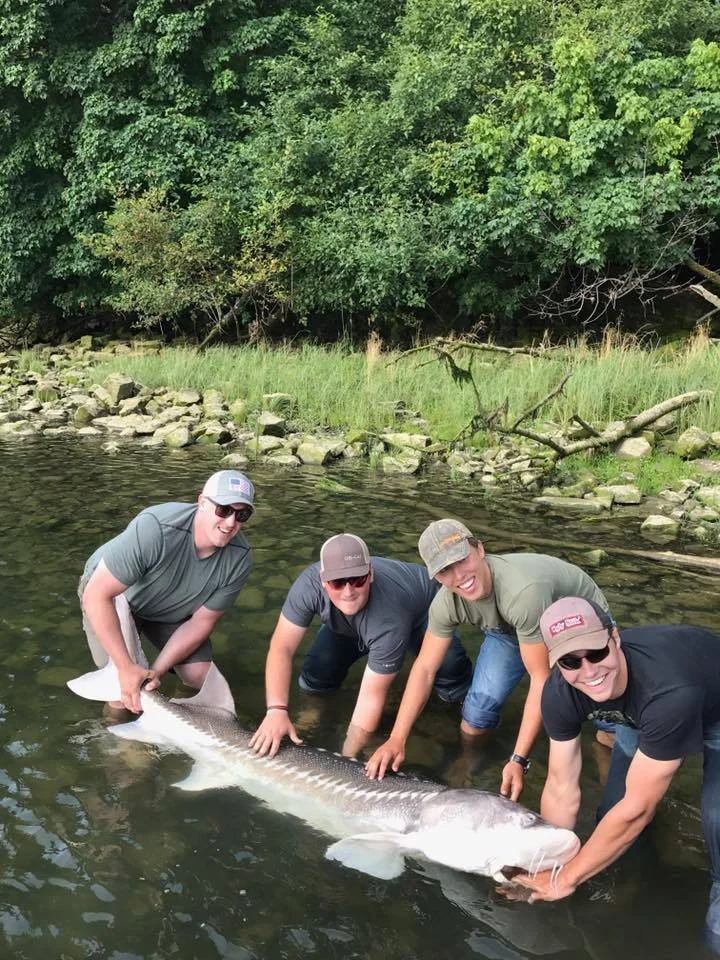 fishermen holding onto large sturgeon caught with fishing charter in Oregon