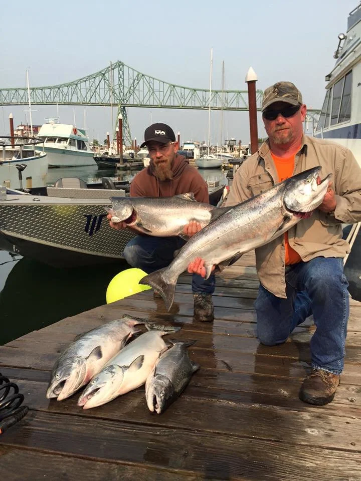fishermen holding up silver chinook salmon caught with fishing charter in Oregon