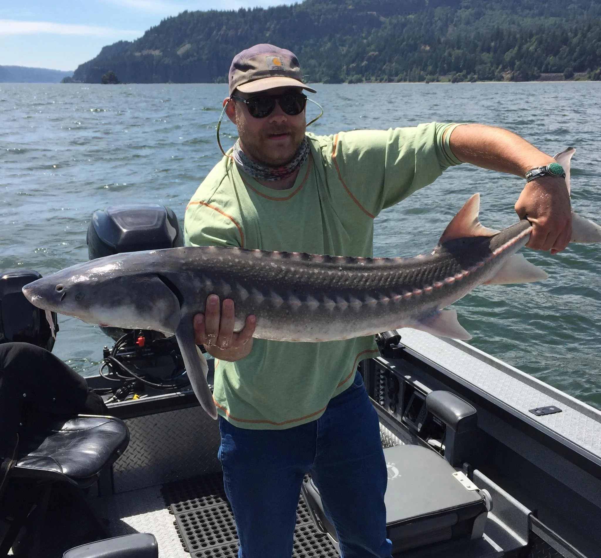 fisherman holding up sturgeon caught with fishing charter in Oregon