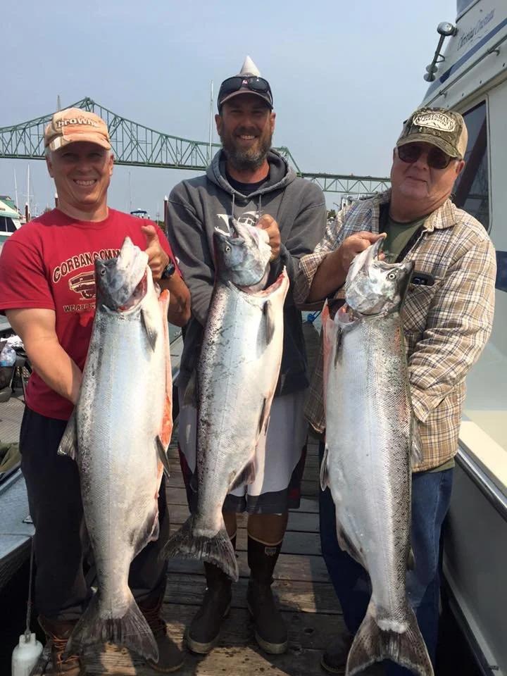 fishermen holding up silver chinook salmon caught with fishing charter in Oregon
