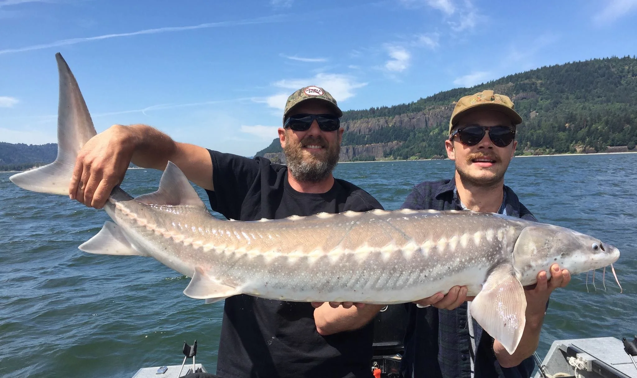 fishermen holding up sturgeon caught with fishing charter in Oregon