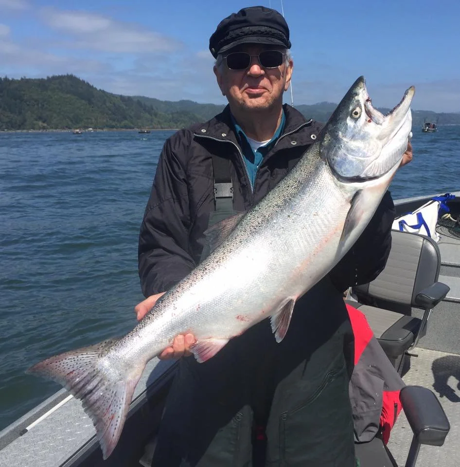 fisherman holding up silver chinook salmon caught with fishing charter in Oregon