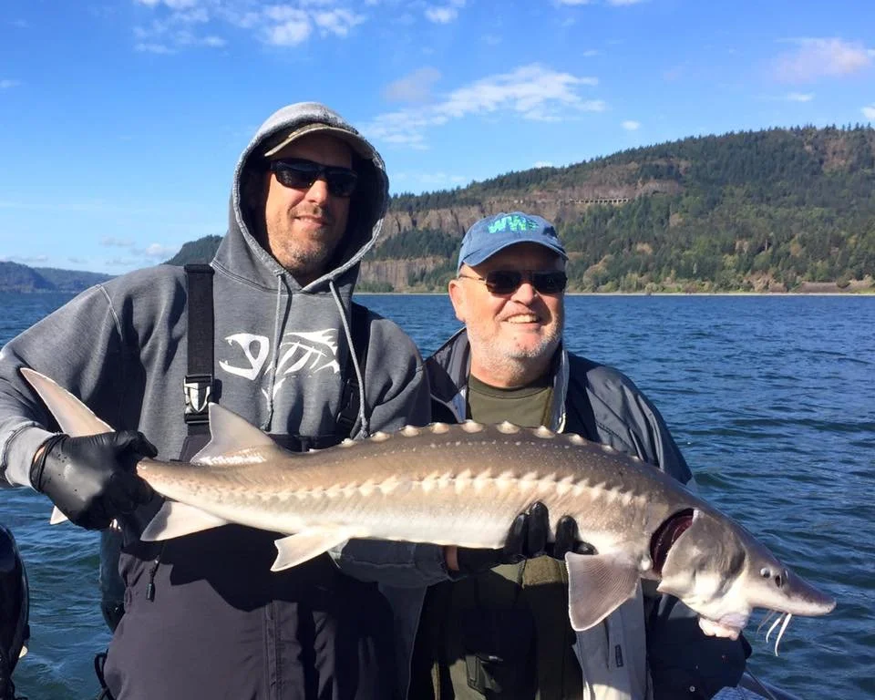 fishermen holding up sturgeon caught with fishing charter in Oregon