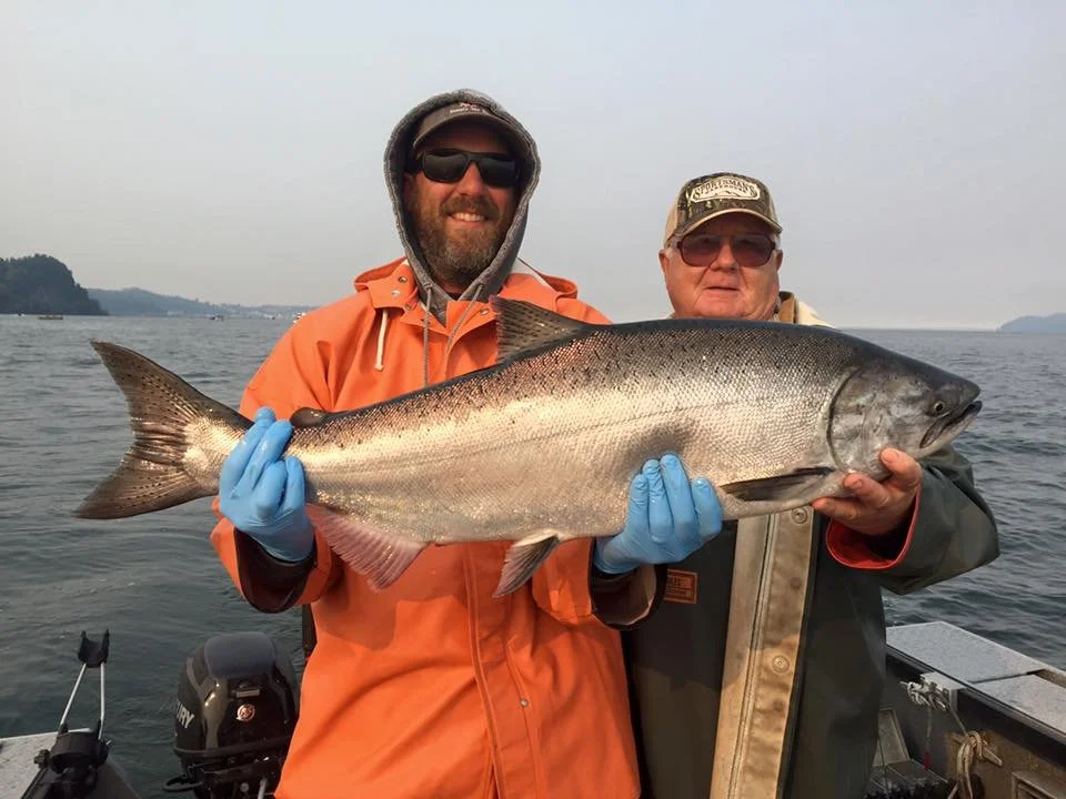 fishermen holding up silver chinook salmon caught with fishing charter in Oregon