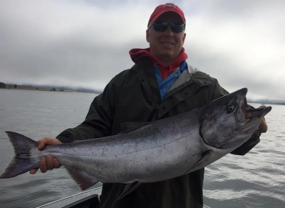 fisherman holding up silver chinook salmon caught with fishing charter in Oregon
