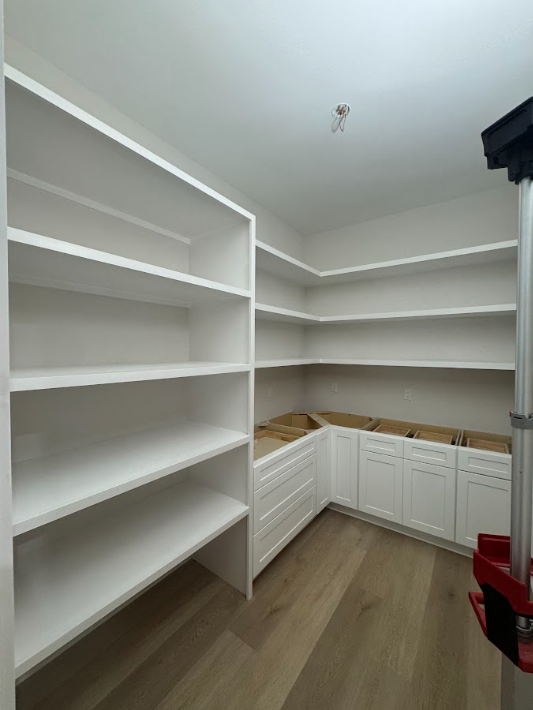 Empty white built-in shelves and cabinets in a room under construction or renovation.