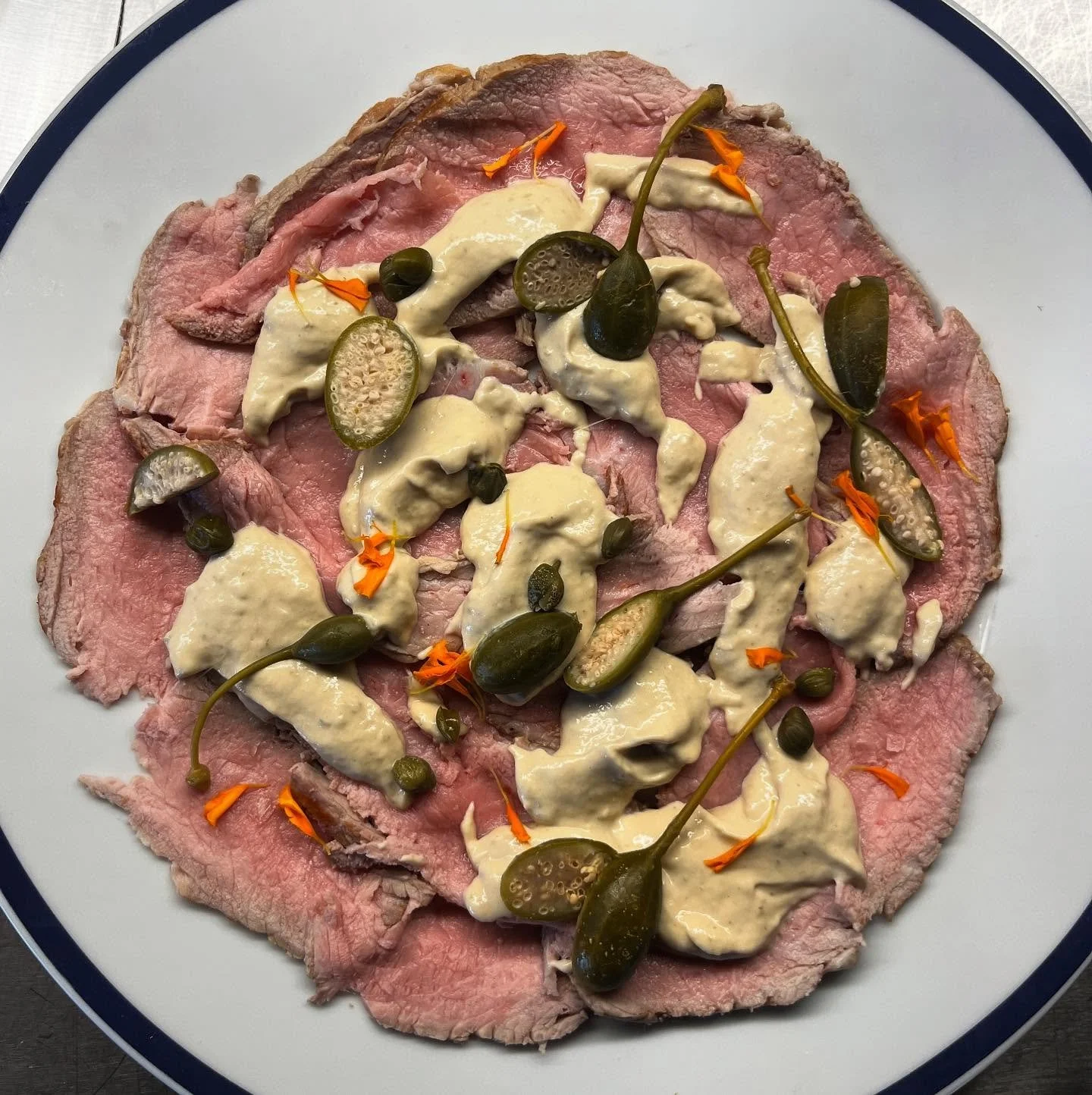 Vitello tonnato &mdash; where land meets sea.
Ros&eacute;-cooked white veal bavette, veal jus, and a creamy sauce of tuna and Cantabrian anchovies. Finished with capers and caper berries for a bold, balanced bite.
Italian tradition, reimagined in Mal