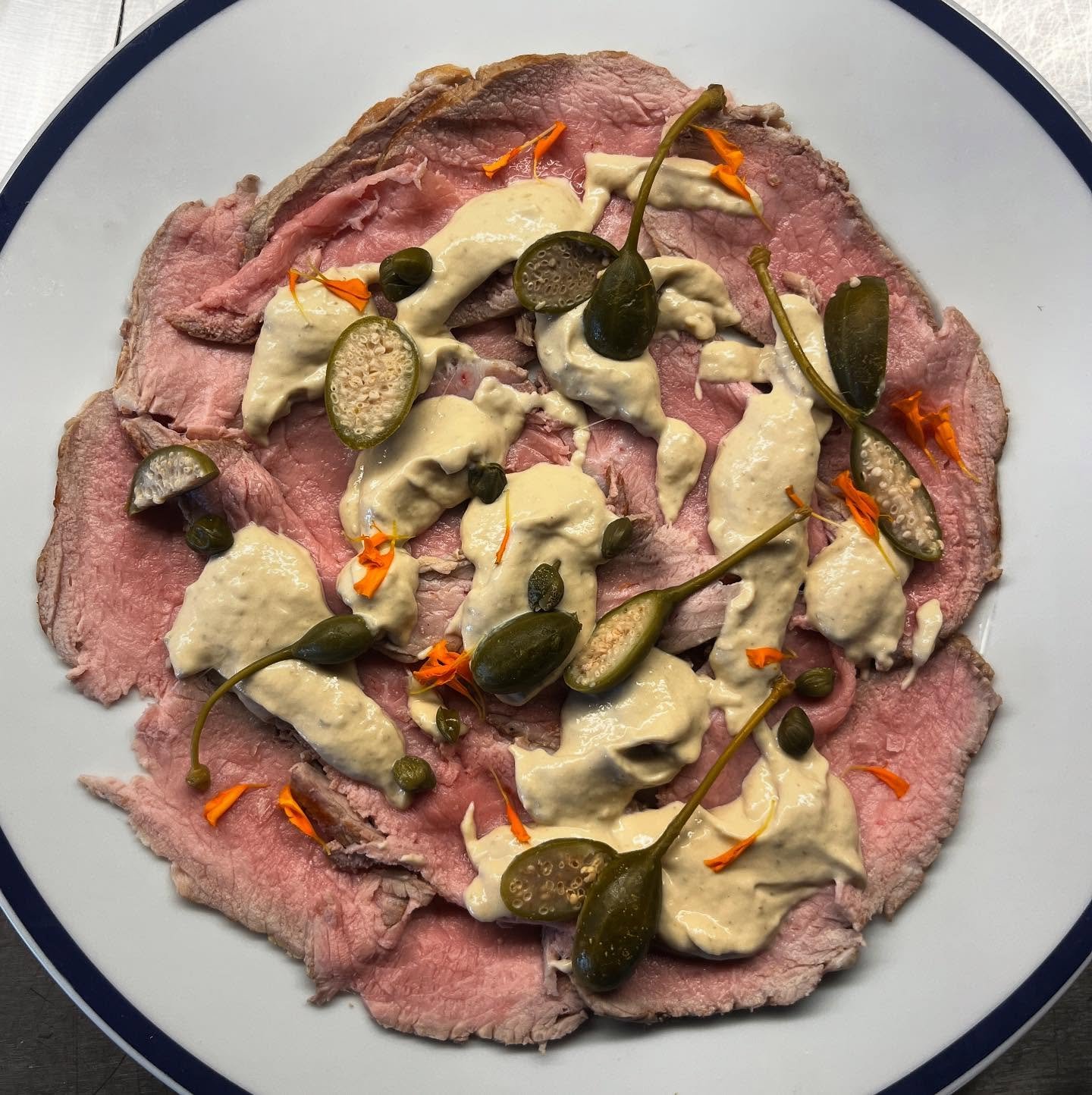 Vitello tonnato &mdash; where land meets sea.
Ros&eacute;-cooked white veal bavette, veal jus, and a creamy sauce of tuna and Cantabrian anchovies. Finished with capers and caper berries for a bold, balanced bite.
Italian tradition, reimagined in Mal