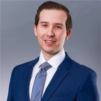 Porträt eines jungen Mannes in formeller Kleidung vor grauem Hintergrund