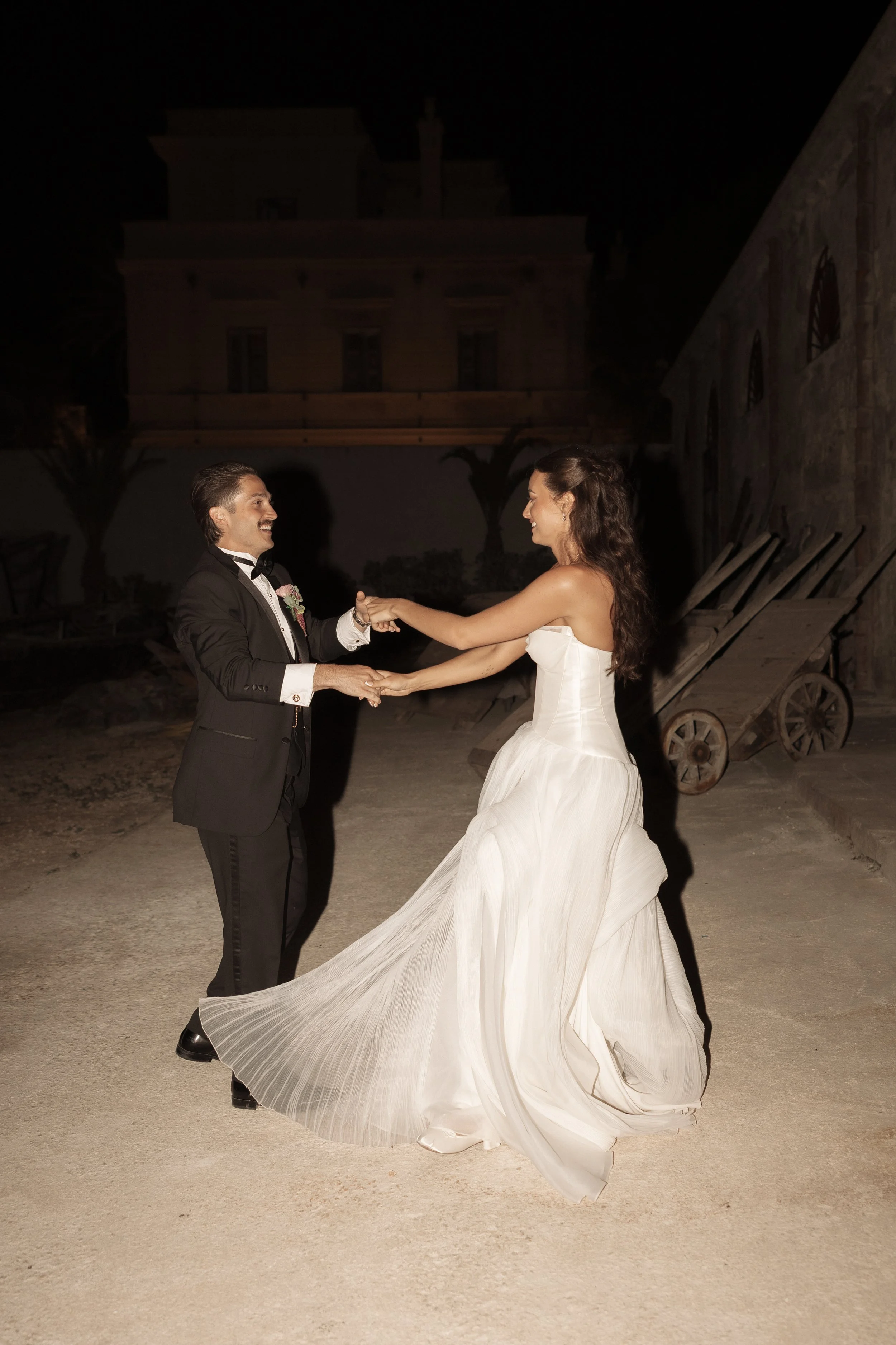 Editorial nighttime wedding portrait of Savannah and Todd dancing at Camparia Favignana in Sicily, with the bride's flowing gown captured in motion.