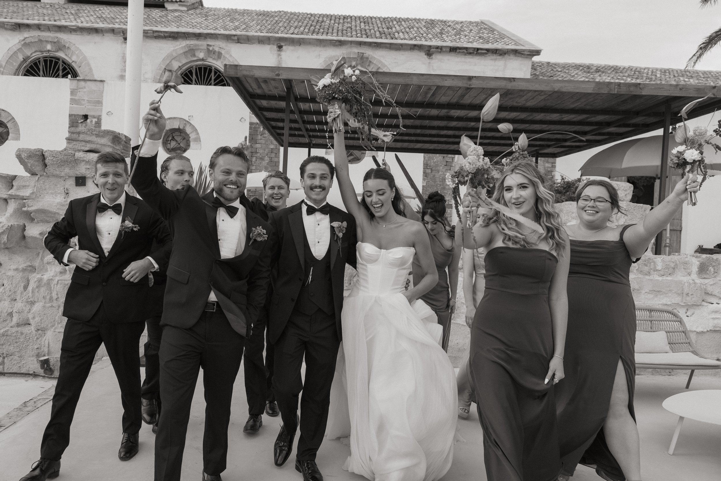 Documentary-style wedding photograph of Savannah and Todd celebrating with their wedding party on the island of Favignana, Sicily.