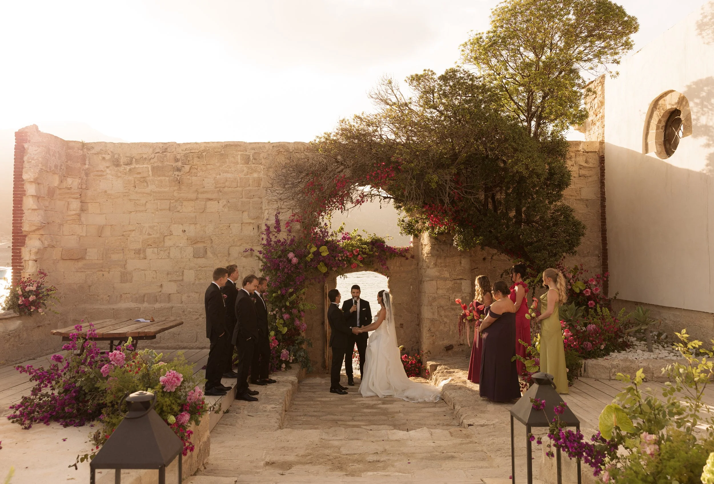 Savannah and Todd's outdoor wedding ceremony at Camparia Favignana, surrounded by vibrant floral arrangements and guests.