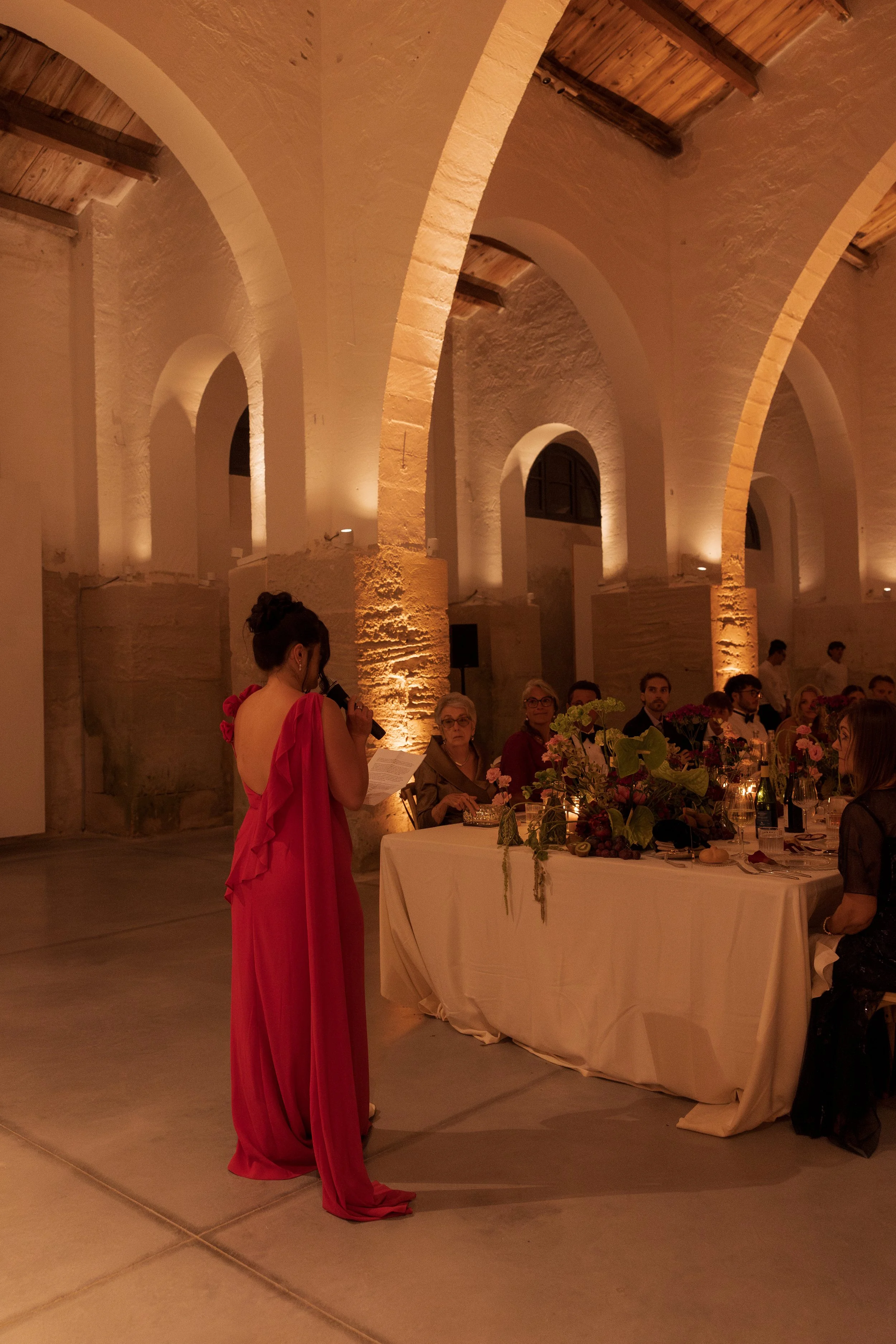 Documentary wedding photograph of guests enjoying an intimate candlelit reception beneath the stone arches of Camparia Favignana in Sicily.