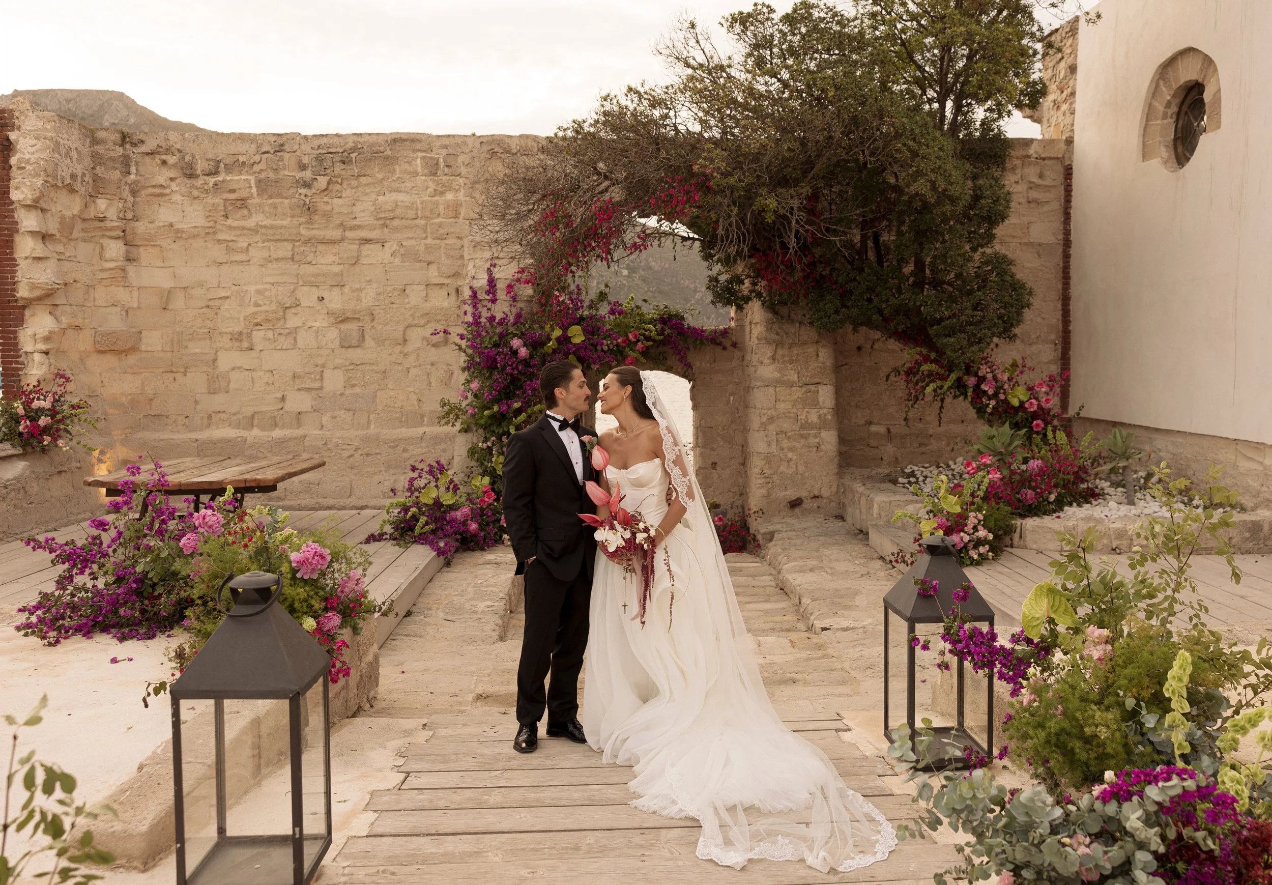 Editorial wedding portrait of Savannah and Todd surrounded by colorful flowers and historic stone architecture at Camparia Favignana.