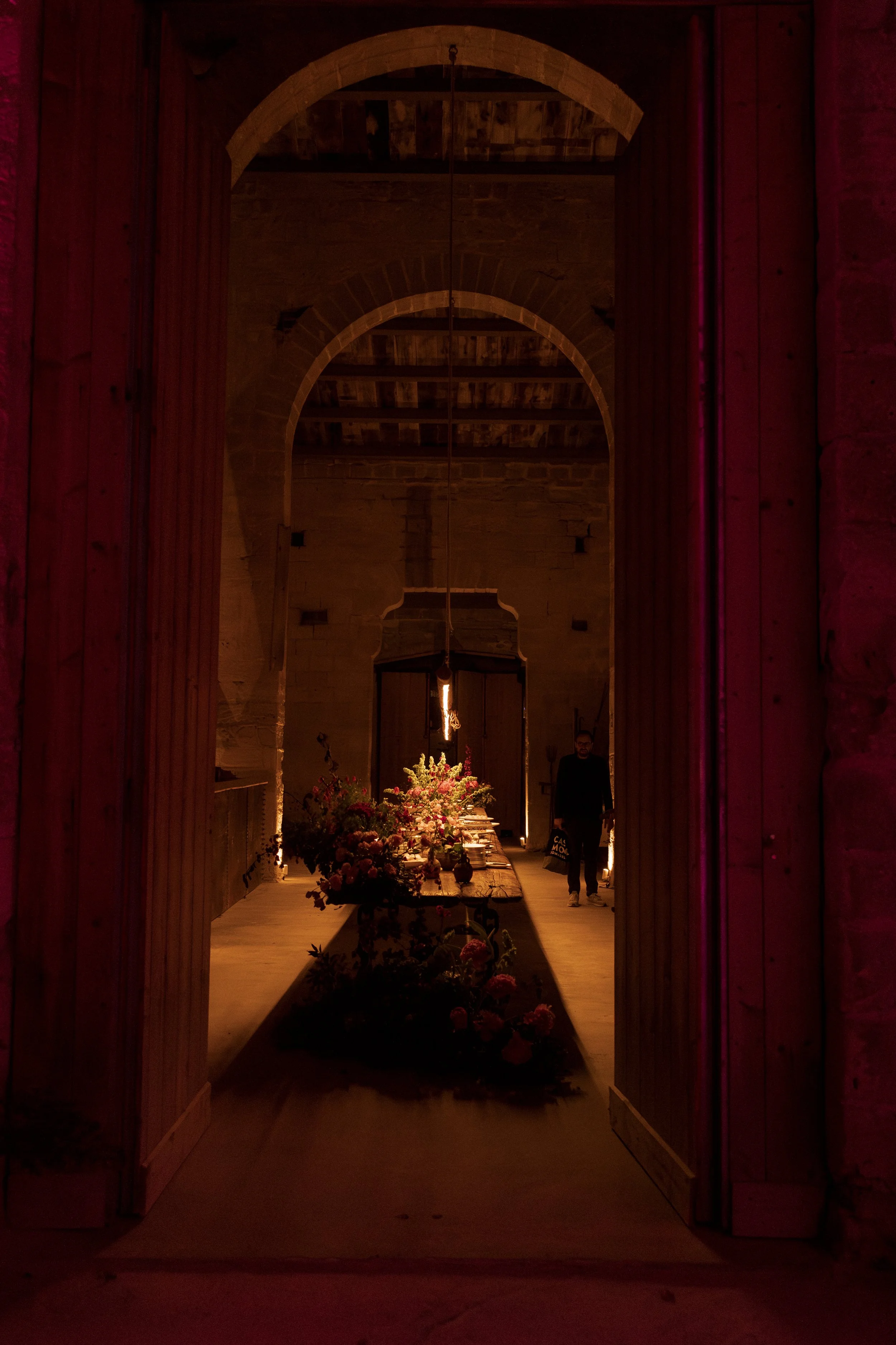 Wedding floral installation featuring a wooden boat and vibrant pink flowers inside the historic Camparia Favignana reception venue.
