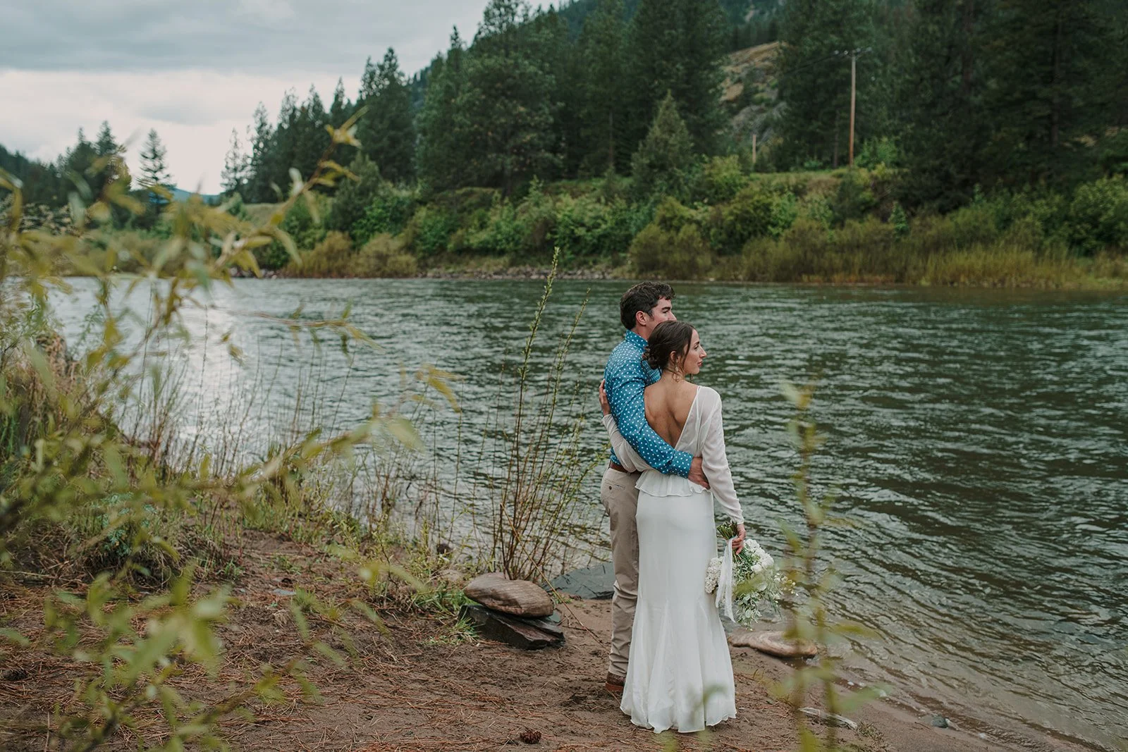 Bride and groom sharing a quiet moment by the river after wedding ceremony at outdoor venue in Missoula, MT.