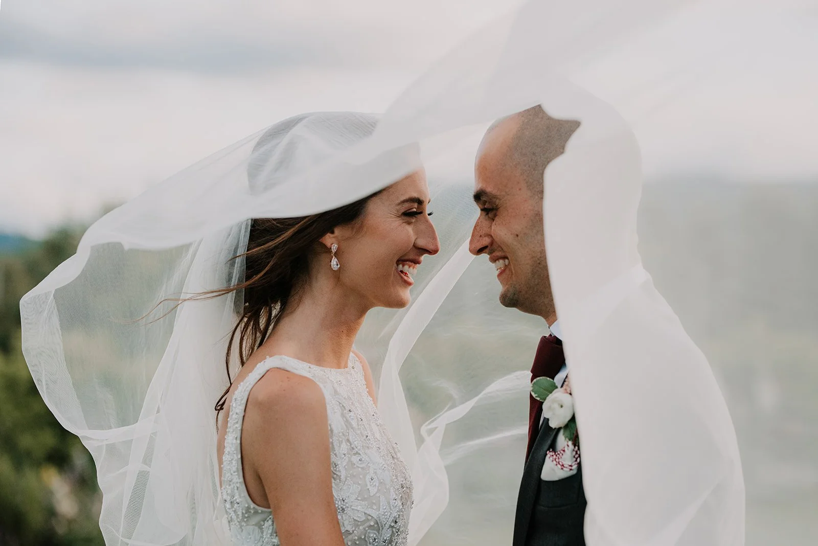 Bride and groom laughing under veil at golden hour portrait session, outdoor wedding ceremony in the Columbia River Gorge.