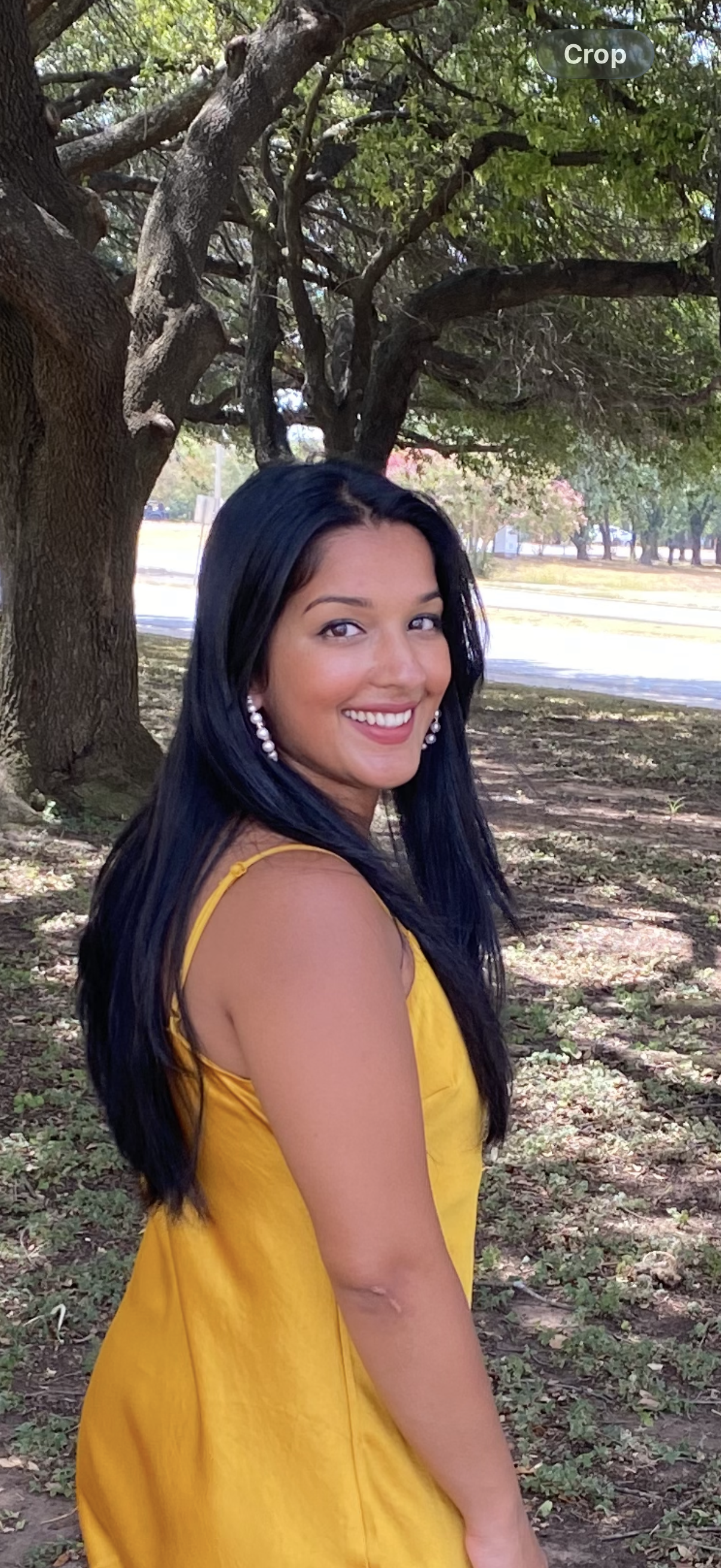 A woman in a yellow dress with black hair smiling