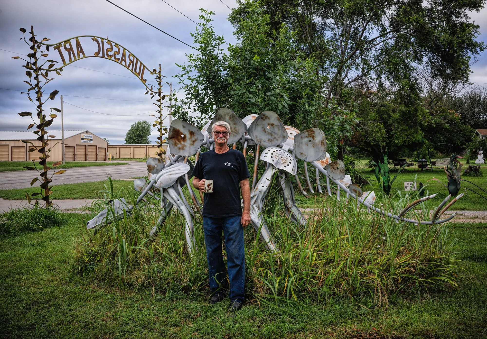 Phil Brinkley with his Stegosaurus sculpture at his Jurassic Art site. Wichita, Kansas. 2025.