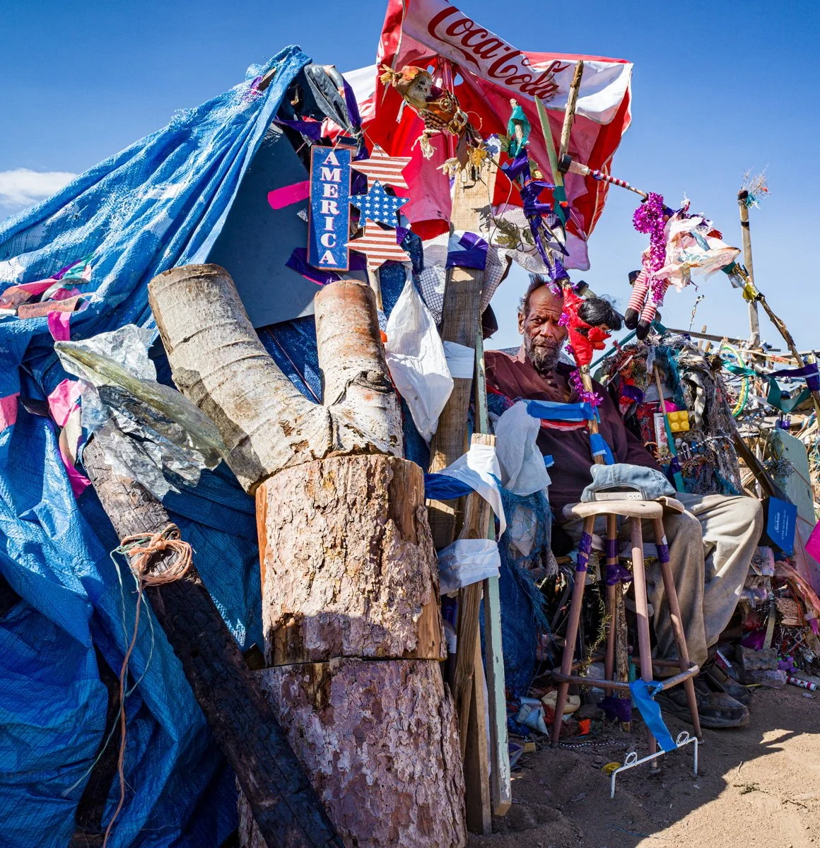 Roy Smith sitting among objects in his compound, “Royville.” Outside Saguache, Colorado. 2020.