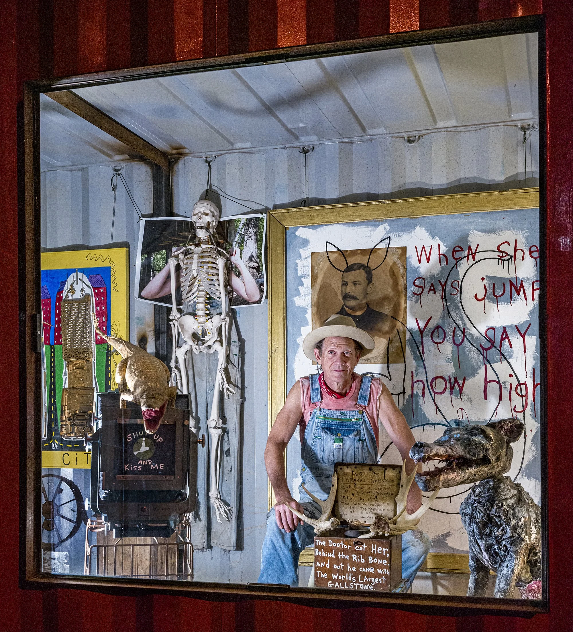 Butch Anthony posed as an artifact at 4 A.M., seated behind the “World’s Largest Gallstone.” Drive-Thru Museum of Wonder. Seale, Alabama. 2021.