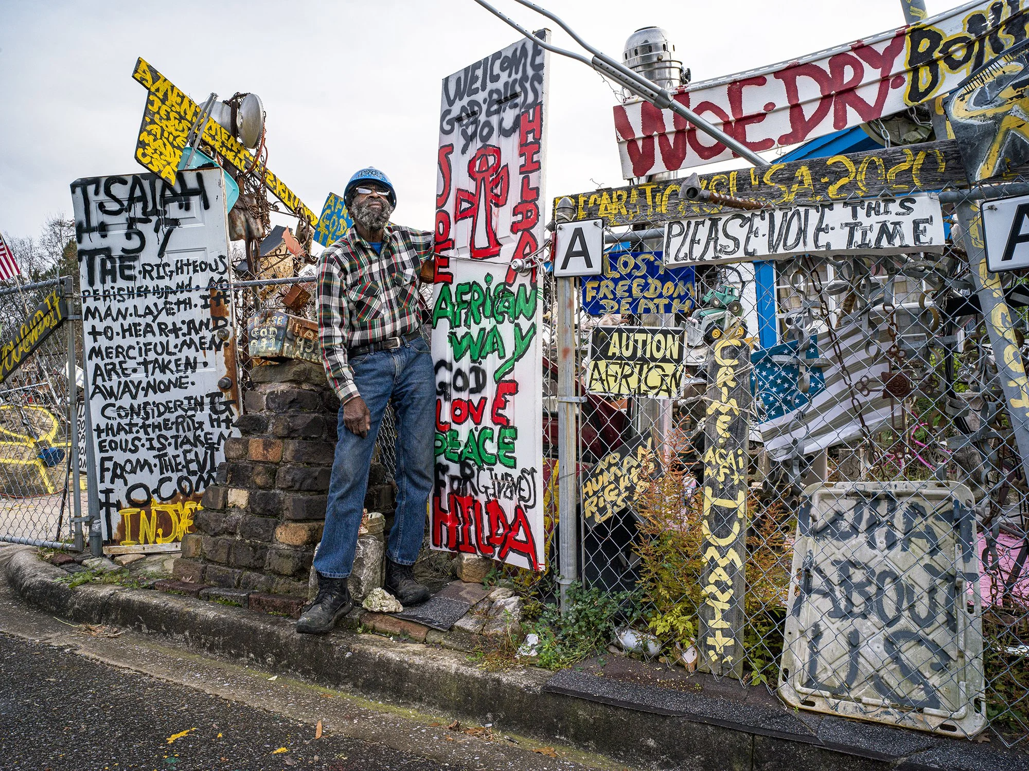 Joe Minter with several signs from his “African American Village in America.” Birmingham, Alabama. 2023.