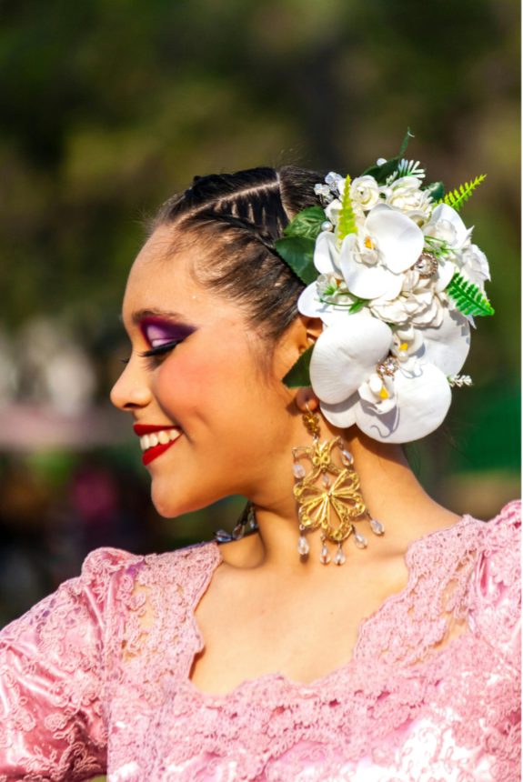 A woman in traditional attire with vibrant makeup, floral accessories, and jewelry, smiling with her eyes closed after receiving cultural identity therapy in NYC.