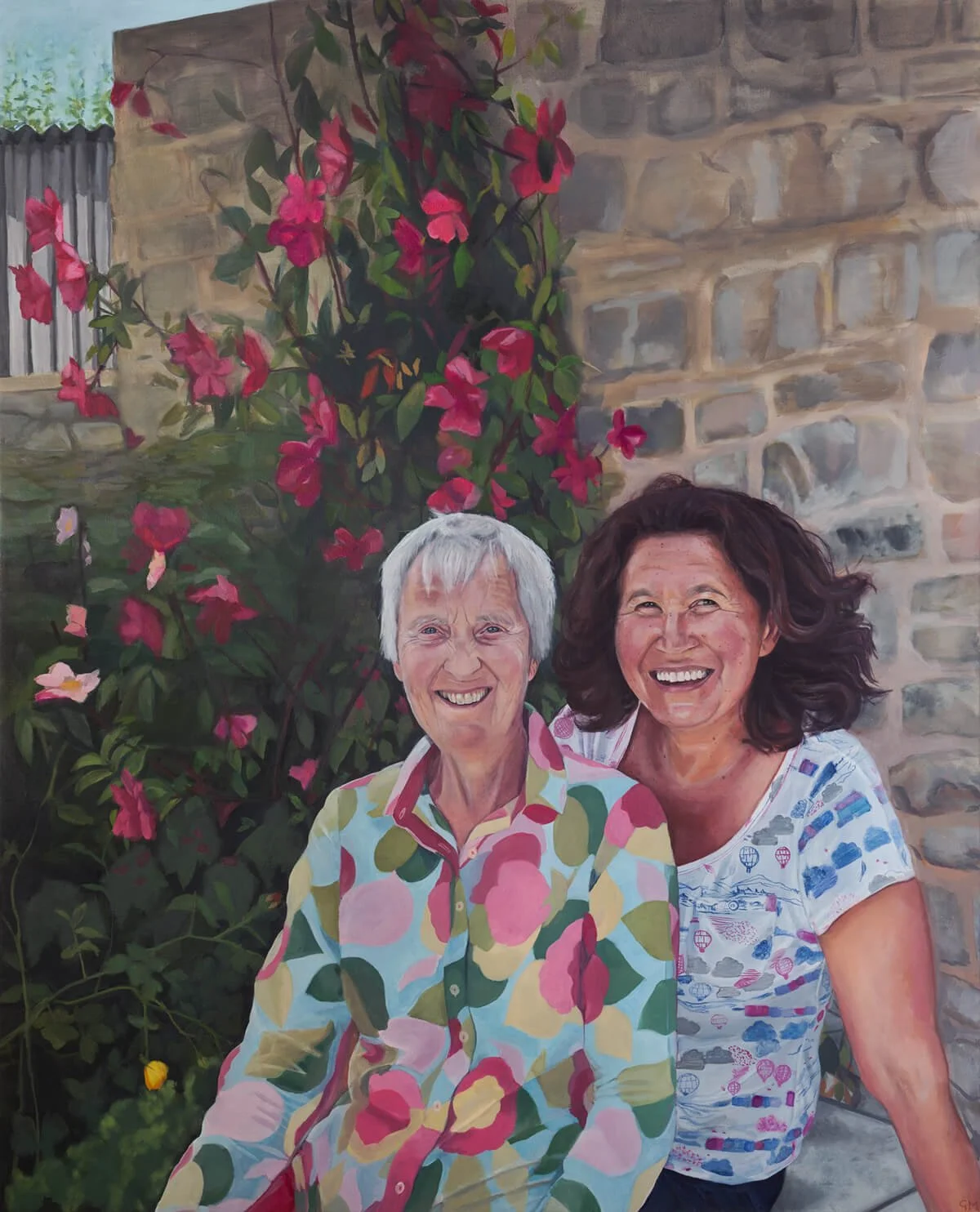 Oil portrait of Anne and Susie who are smiling and sitting in front of a wall with pink roses behind them