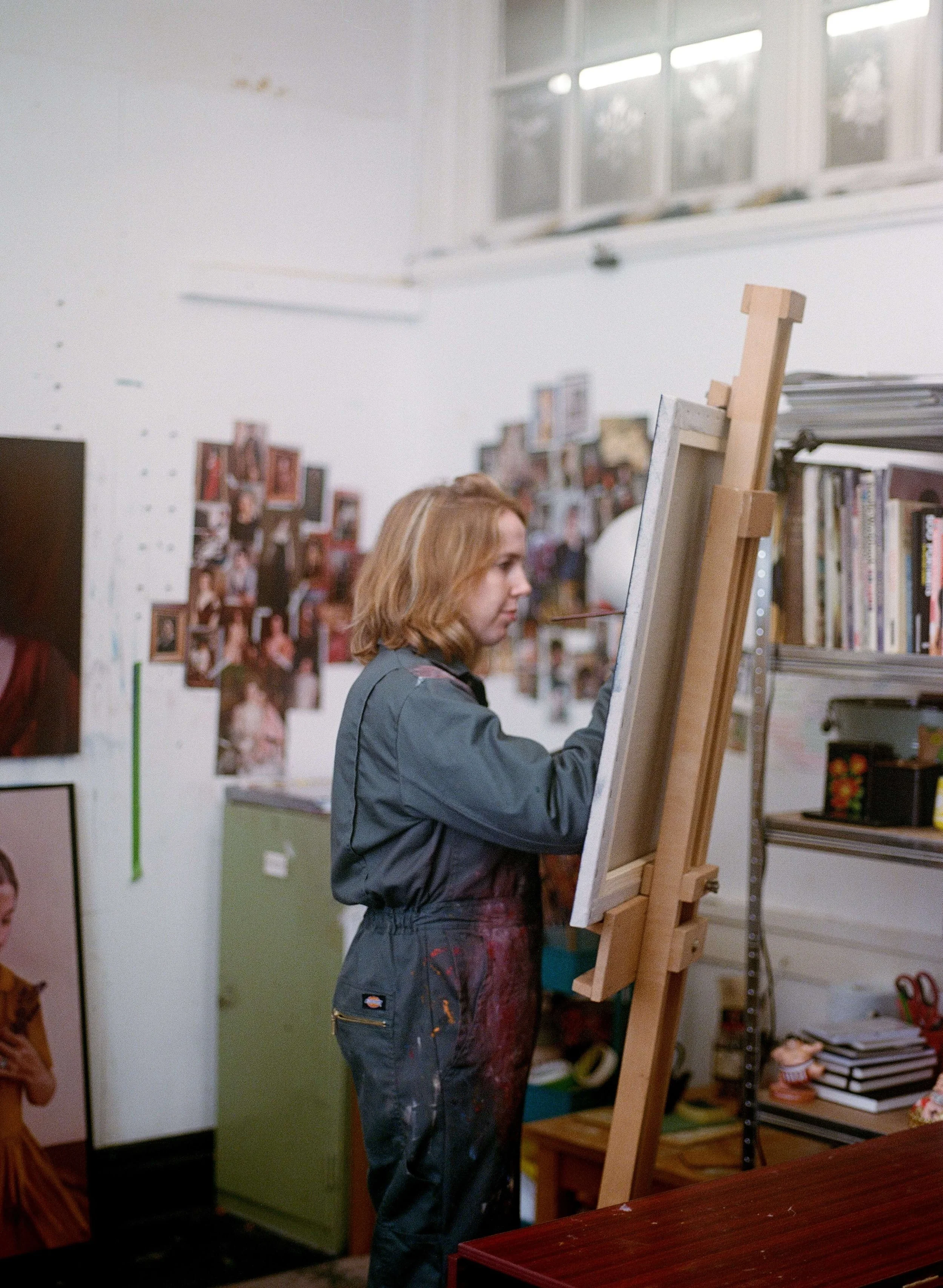 Photo of Genevieve painting on an easel in her painting studio