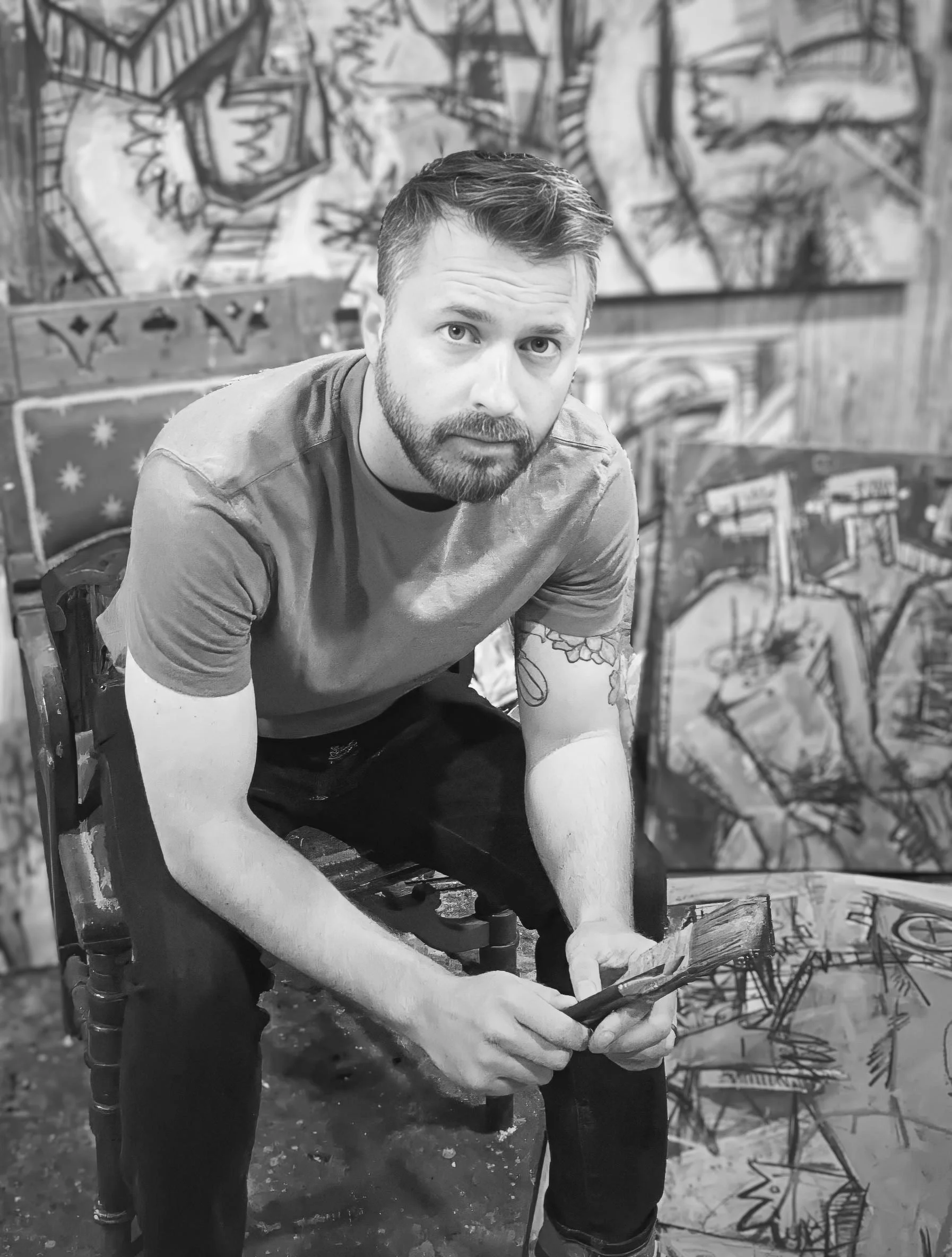 A photographic portrait of Louisville based Artist, Joshua Jenkins, in his home studio infront of a wall of original paintings.