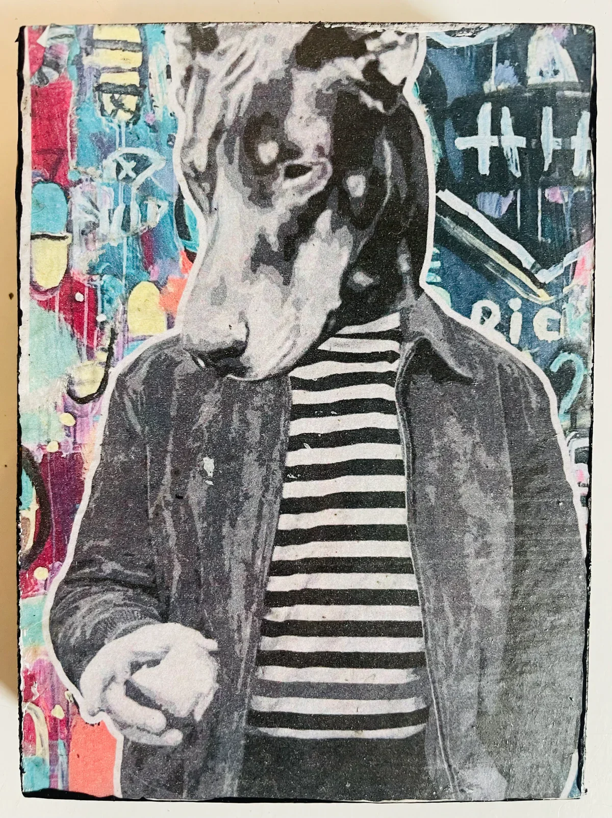 A mixed media artwork featuring a woman with dark hair, wearing a striped shirt and jacket, with a colorful graffiti background.