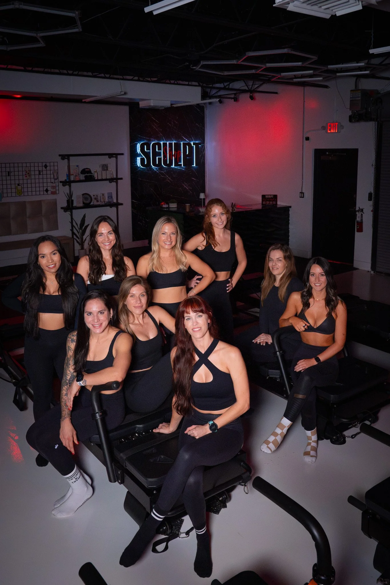 Group of women in workout attire at a fitness studio with "Sculpt" sign
