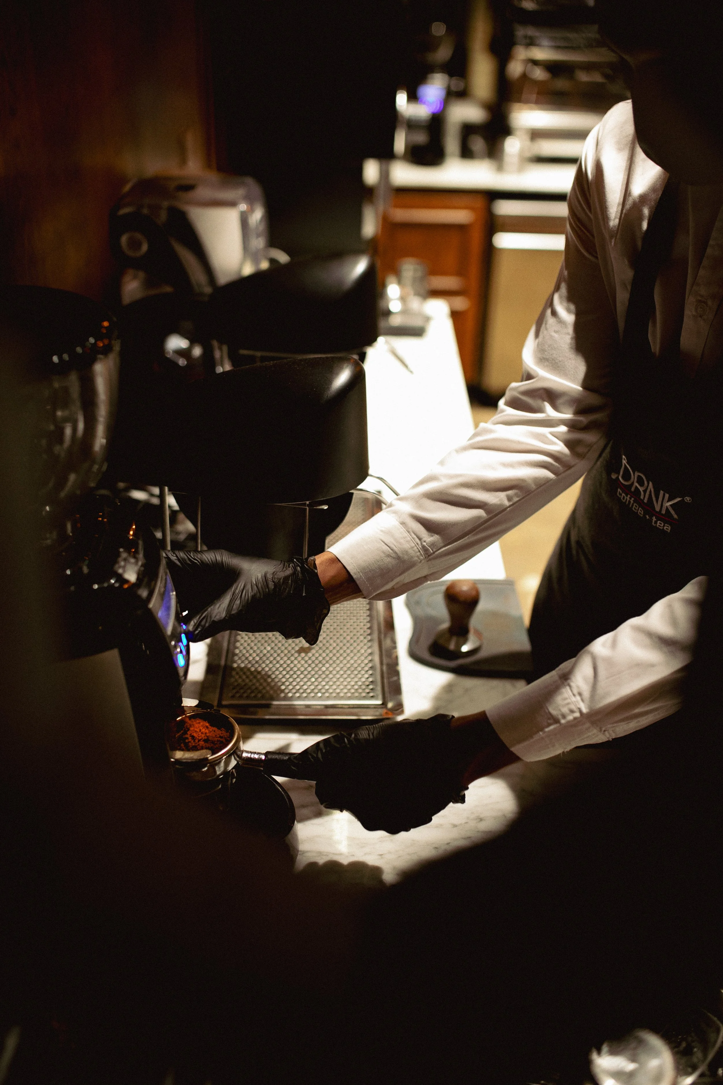 Barista preparing espresso with grinder and portafilter on countertop.