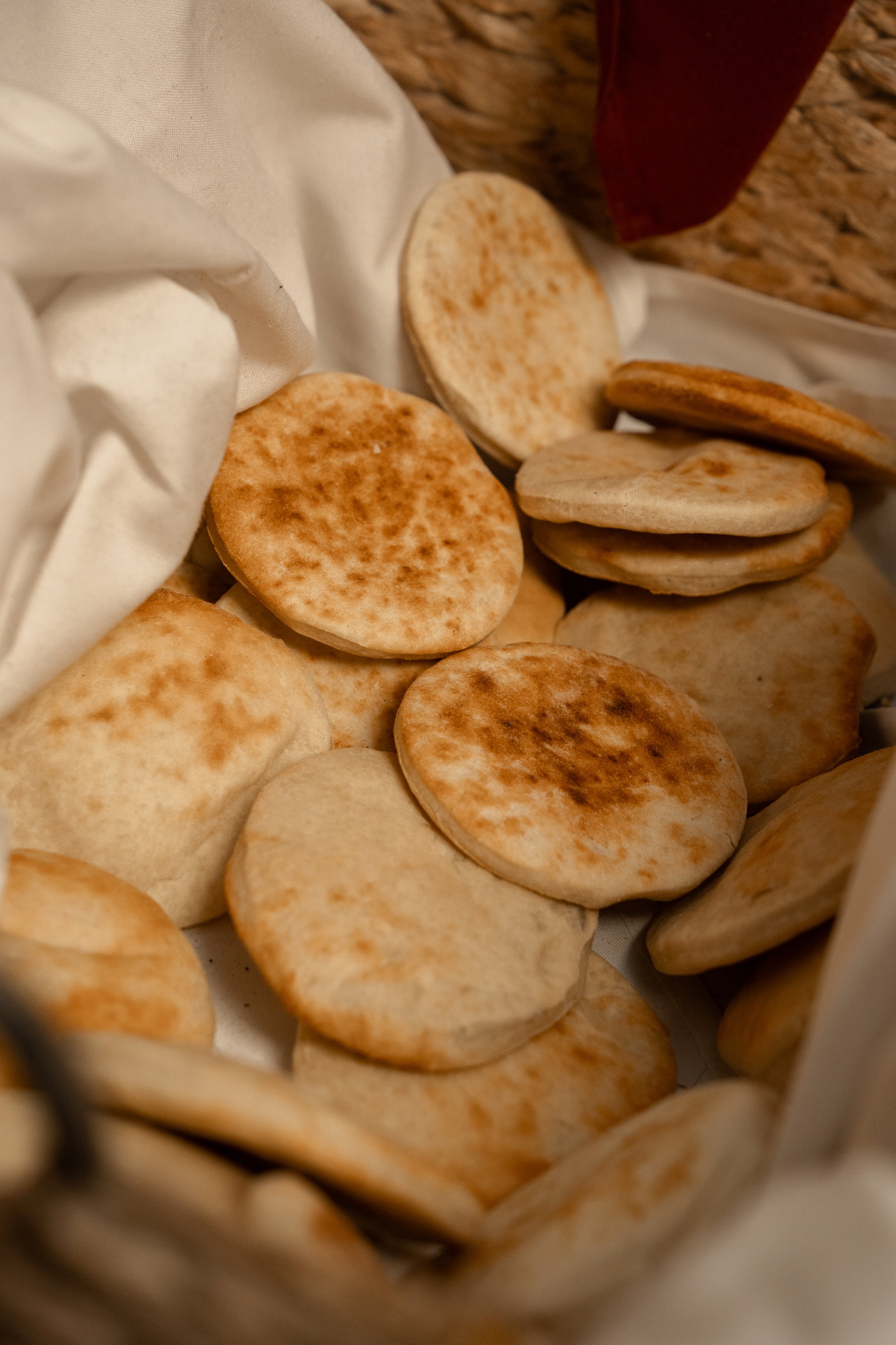 Basket of round pita bread served in a cloth-lined container.