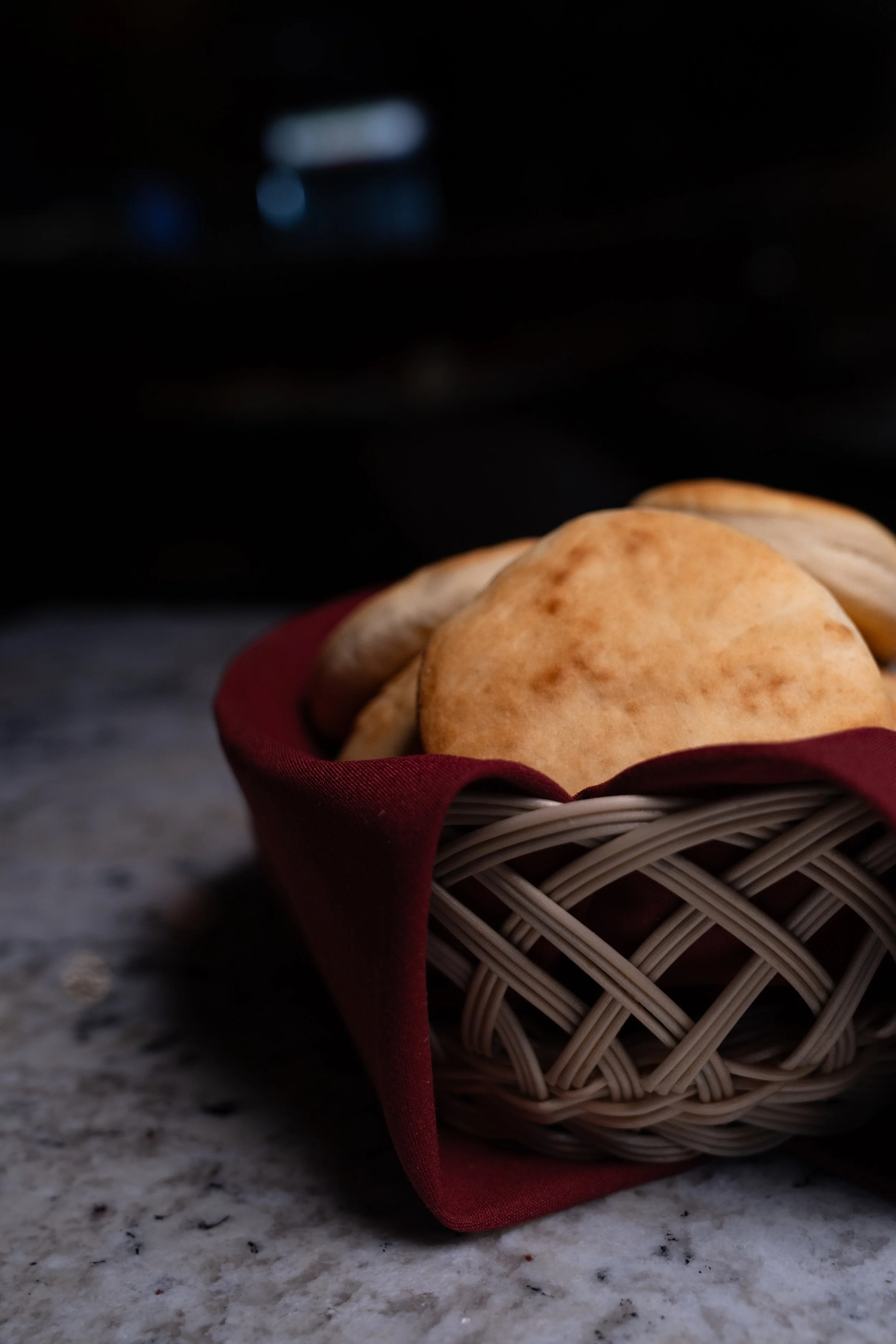 Basket of pita bread on a marble surface.