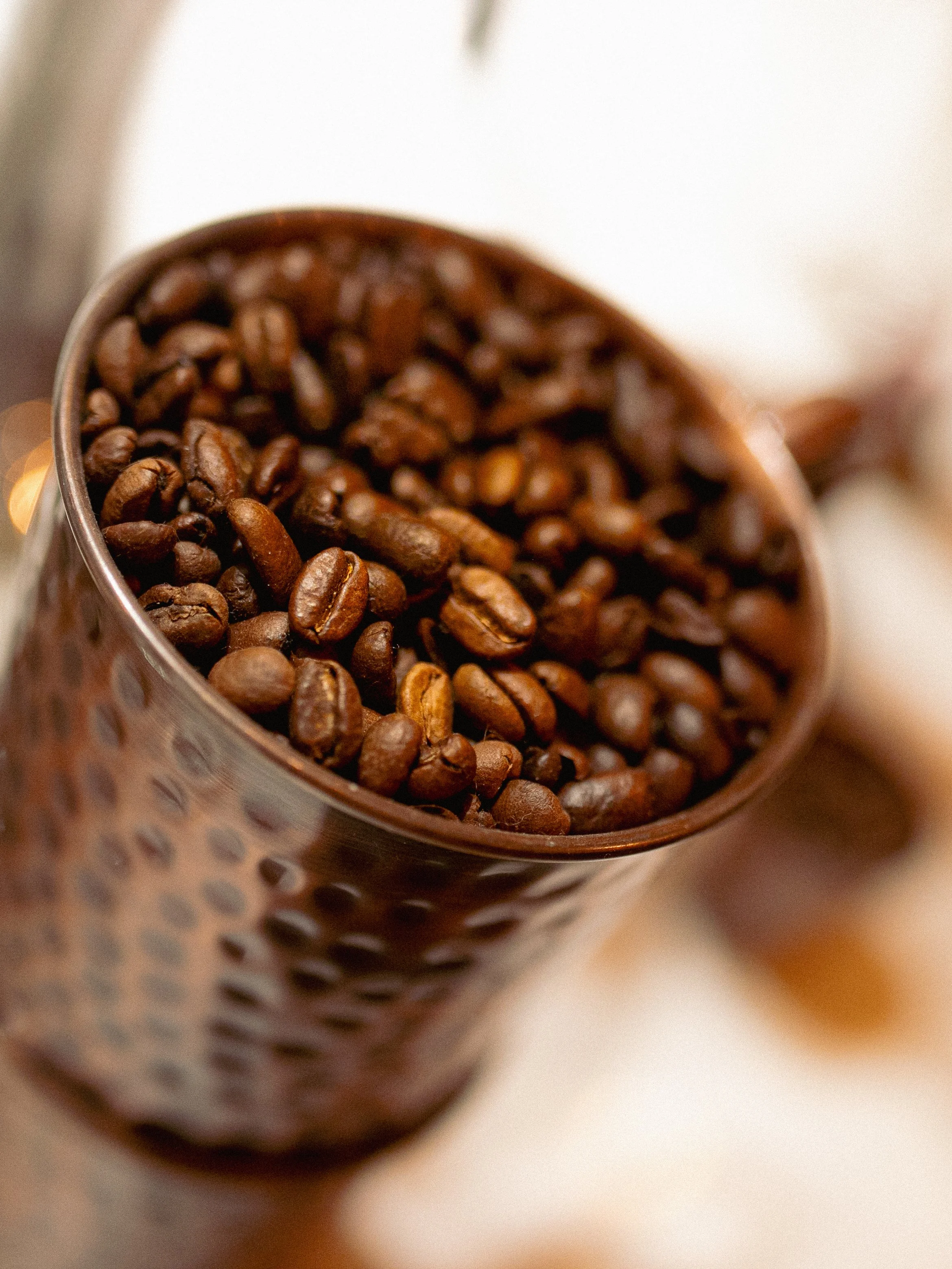 Close-up of coffee beans in a textured brown container.