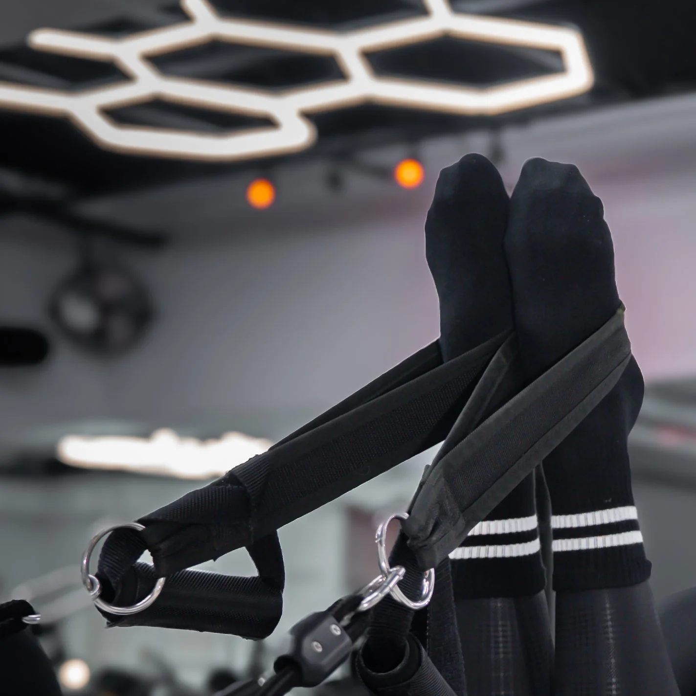 Person's feet in hammocks during an aerial yoga session in a gym