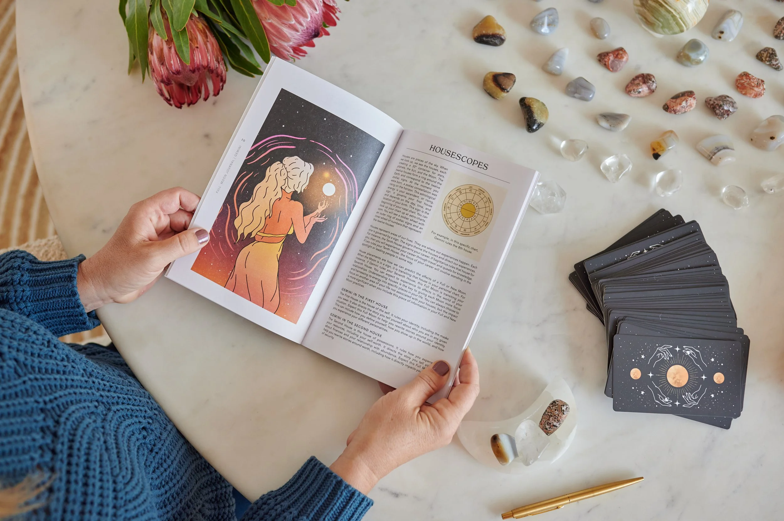 spirit daughter workbook with manifestation card deck alongside. crystals in upper righthand corner. pink flowers in upper lefthand corner.
