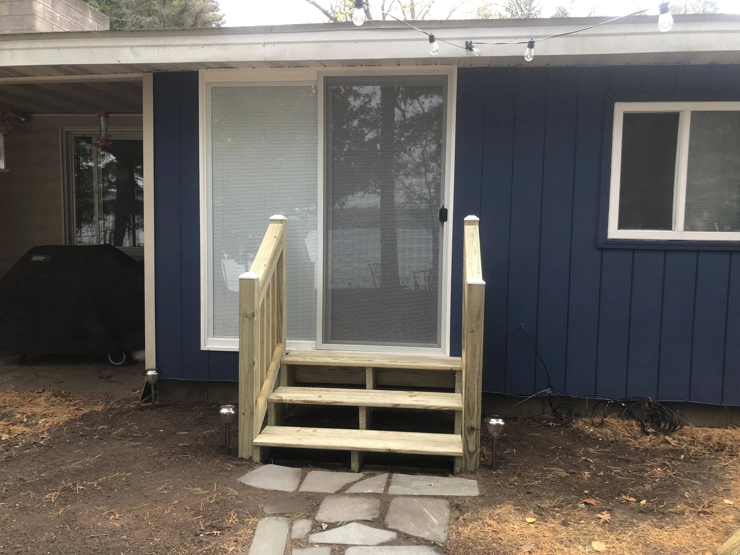 After installation of new sliding patio door, wood siding and construction on new treated wood steps.