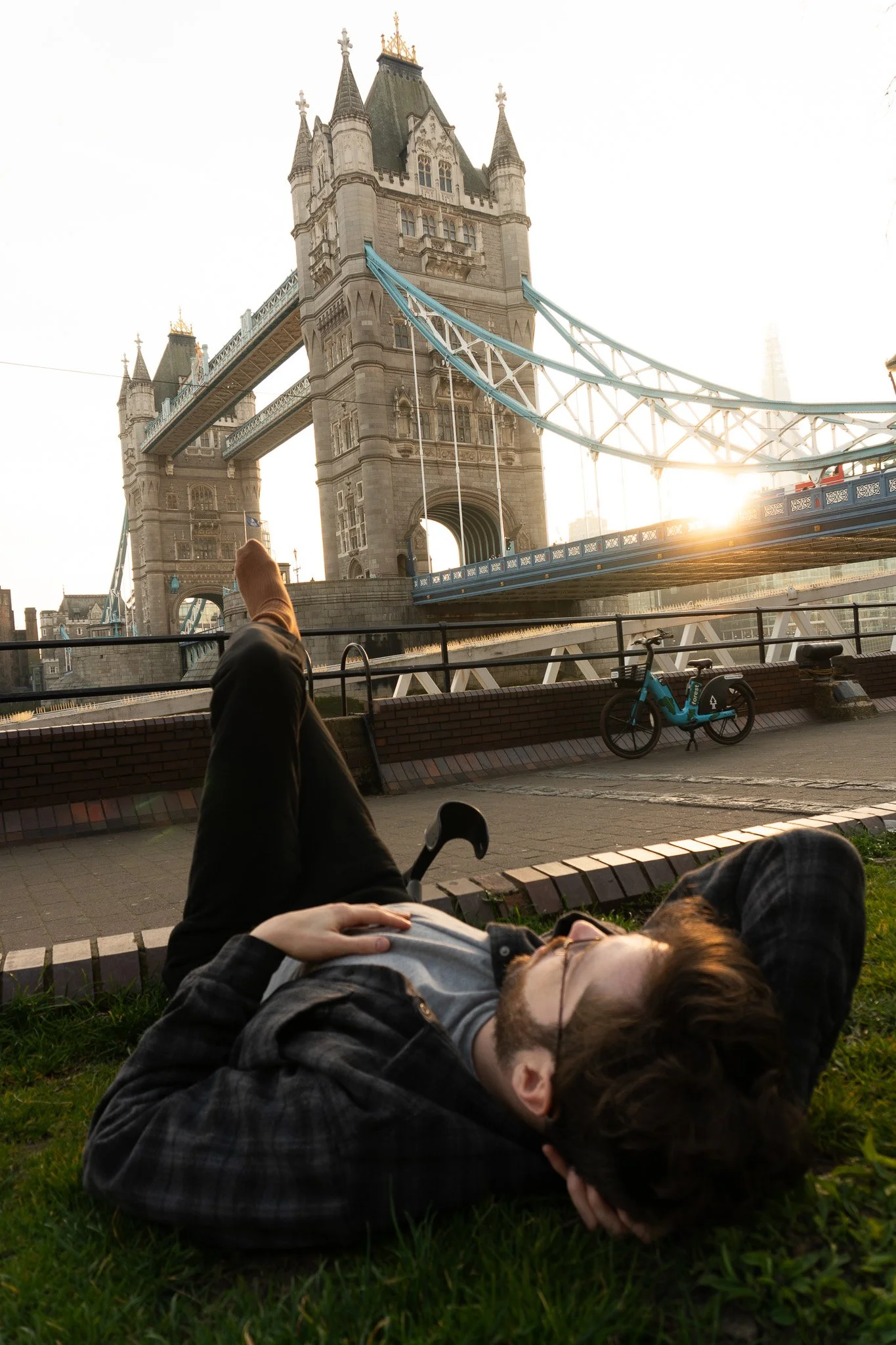 Jack is laying on the grass and looking at the Tower Bridge in front of him