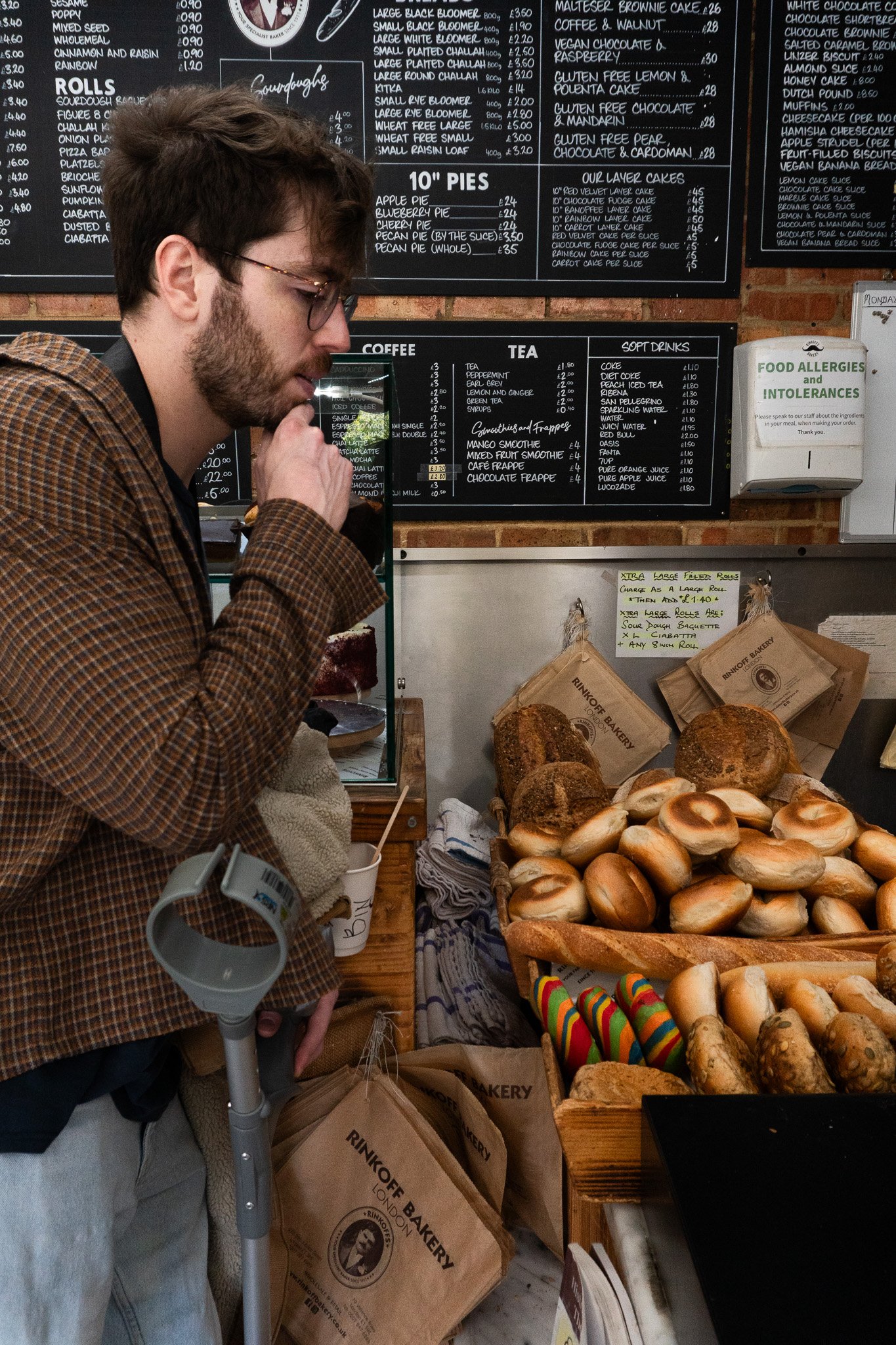 Jack is standing with his crutch in a local bakery and choosing a pastry to buy.