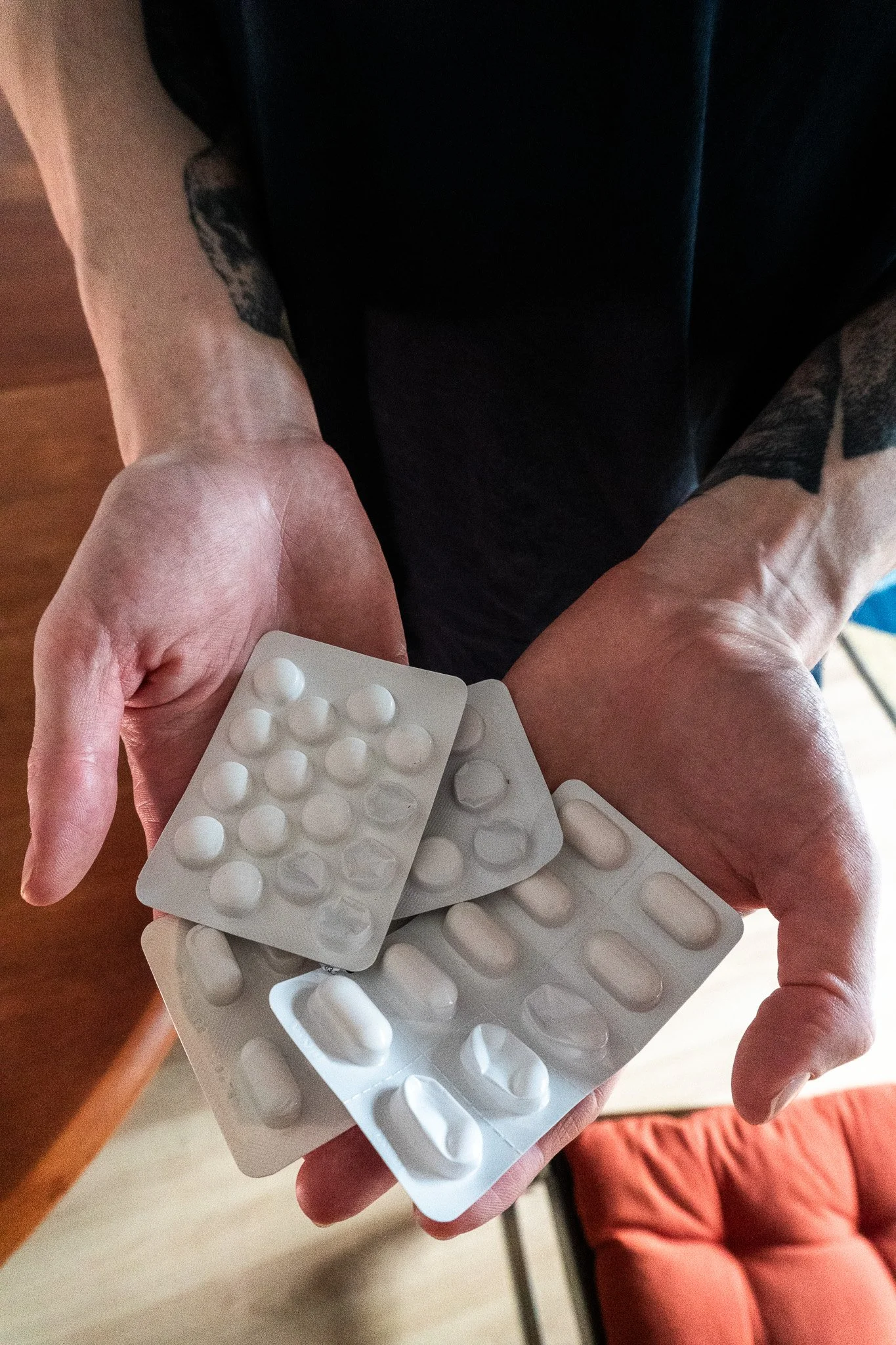 Jack's hands are holding four different types of painkillers that he uses to help his chronic pain