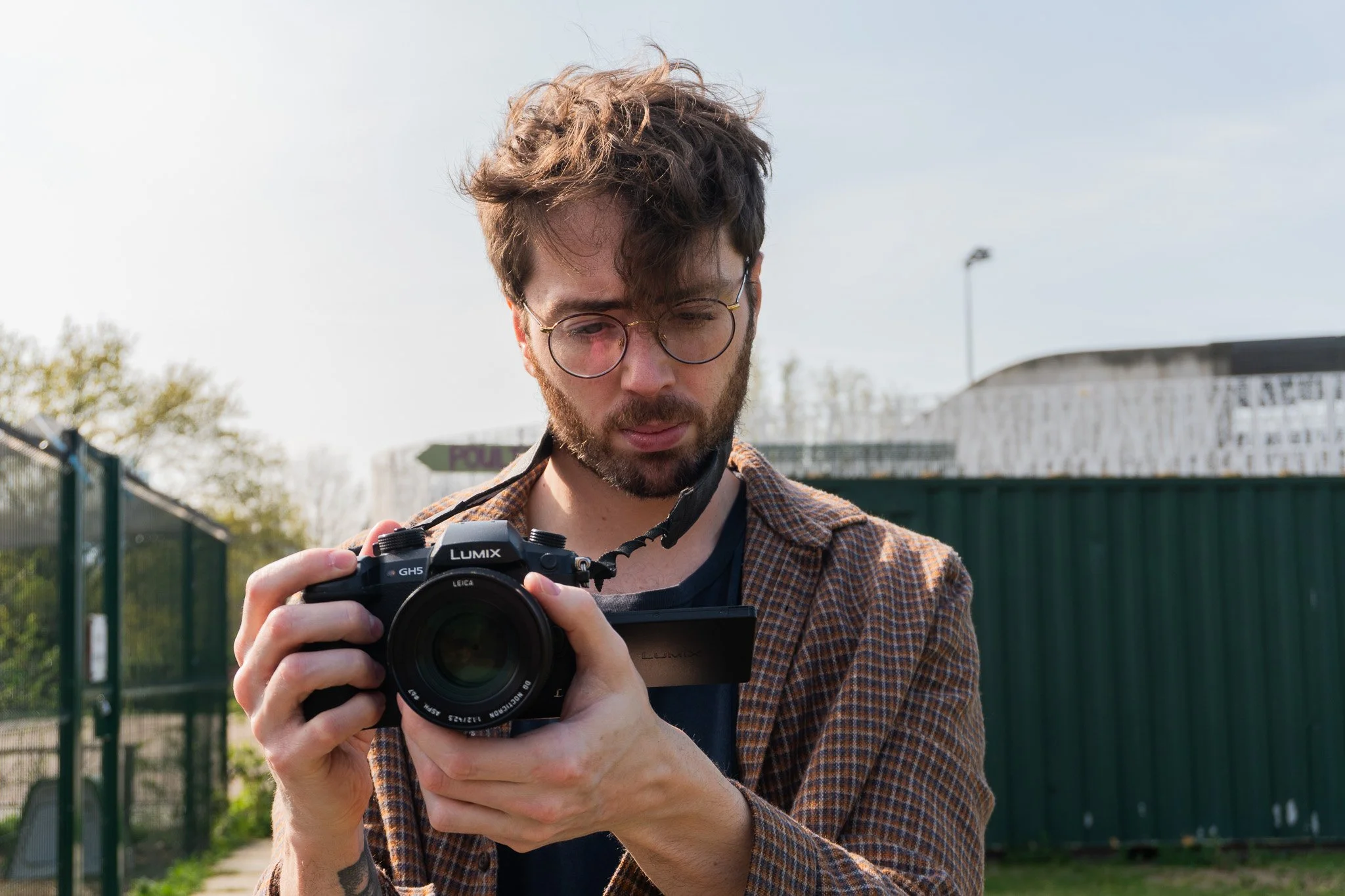 Jack is outside, holding and pointing his Lumix camera.