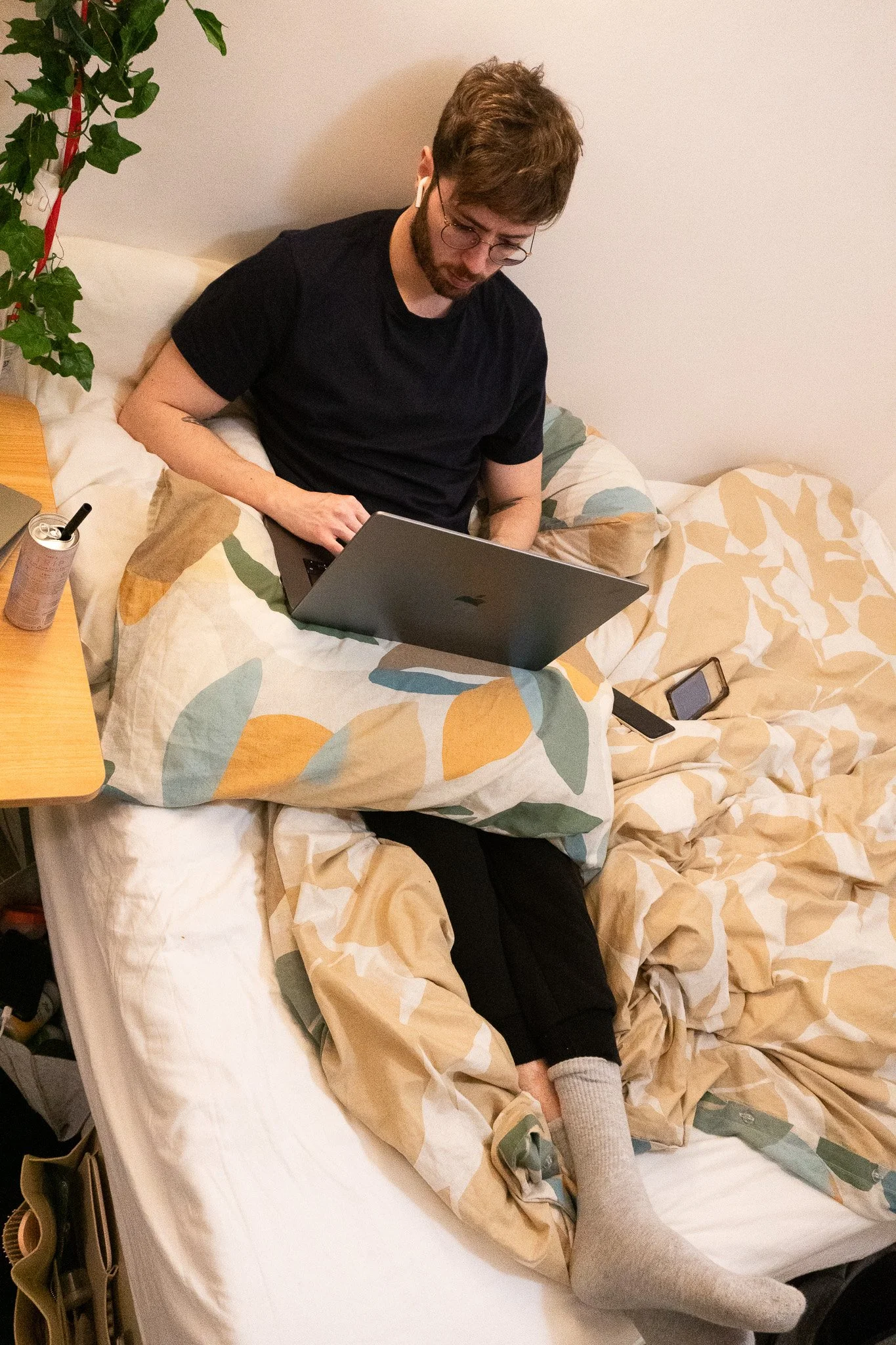 A shot from above. Jack working on his laptop in bed with his leg extended to alleviate his leg pain.