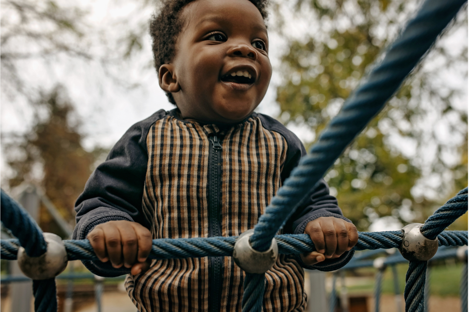👉 Child exploring playground ropes, symbolizing early upbringing shaping beliefs about structure