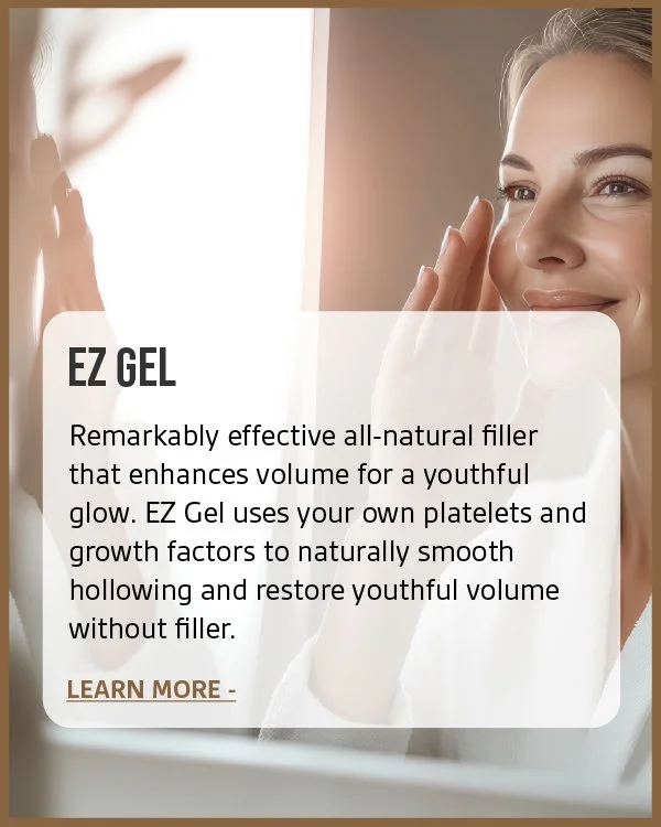 A smiling woman looking at her reflection in the mirror while applying skincare to her face.